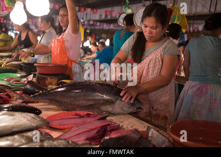 Eine Frau, die einen frischen Thunfisch, im Markt Talisay, Cebu City, Philippinen gut vorbereiten Stockfoto