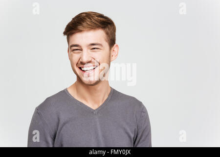 Porträt von fröhlichen Attrative junger Mann im grauen Pullover über weißem Hintergrund Stockfoto