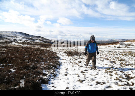 Ein Mann geht durch den Schnee auf einem kalten Ilkley Moor nach starkem Schneefall. Stockfoto