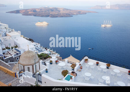 Santorini - die Aussichten von Fira nach Caldera mit der Nea Kameni Insel im Morgenlicht. Stockfoto