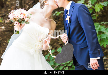 Braut und Bräutigam mit einem Schild in Herzform. Stockfoto