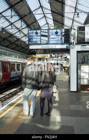 Ein Paar wartet auf einer Plattform in der Londoner U-Bahn Station Earl's Court, Earl's Court, London, England, Vereinigtes Königreich Stockfoto