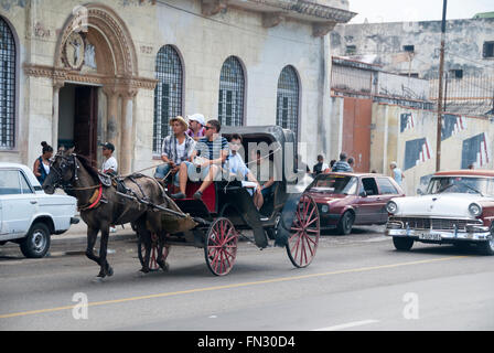 Ein Pferd Pferdekutsche gefolgt von einem Oldtimer Ford Fairlane escort Touristen auf dem berühmten Malecon in Havanna Kuba. Stockfoto