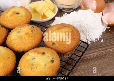 Frisch gebackene Muffins mit Zutaten auf einem Holztisch. Stockfoto