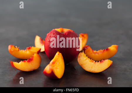 Gelbe Nektarine Pfirsich - ganze Früchte und Scheiben auf dunklen Grunge Hintergrund. Geringe Schärfentiefe. Stockfoto