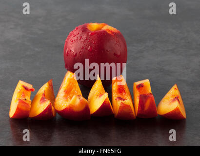 Gelbe Nektarine Pfirsich - ganze Früchte und Scheiben auf dunklen Grunge Hintergrund. Geringe Schärfentiefe. Stockfoto