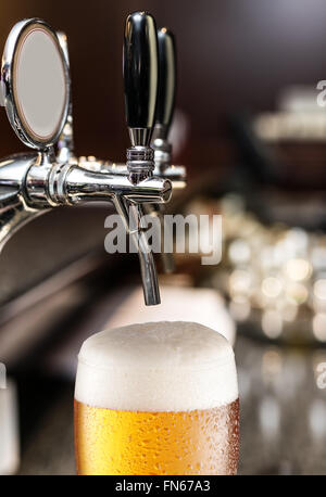Der Prozess der strömenden Bier in das Glas. Datei enthält Beschneidungspfade. Stockfoto