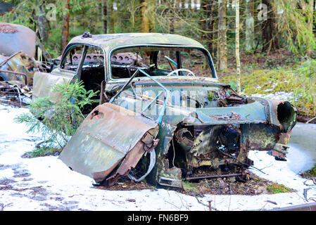 Eine alte und sehr degradiert Junk-Auto in der Natur hinterlassen. Schnee auf dem Boden. Stockfoto