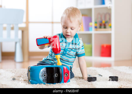 Kind junge Reparaturen Spielzeugauto indoor Stockfoto