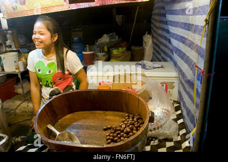 Eine Frau verkauft Kaffeebohnen aus Thailand, die in einer Holzschale auf einer Straße Messe in Kampong Cham, Kambodscha angezeigt werden. Stockfoto