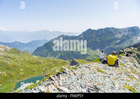 Zwei Menschen sitzen auf den Gipfel des Berges und mit Blick auf weitläufige Panorama auf das Tal und hohe Bergkette des ichs Stockfoto