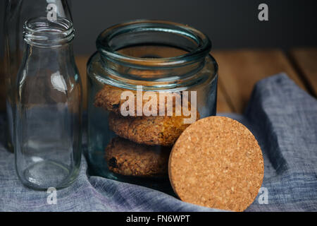 Haferflocken-Cookies im Jar und leere Glasflaschen auf dem Tisch Stockfoto