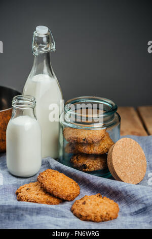 Haferkekse in Glas und zwei Flaschen Milch auf dem Tisch Stockfoto