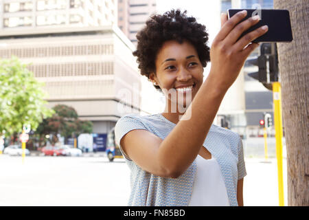 Glückliche junge Afrikanerin auf Stadtstraße nehmen ein Selbstporträt mit ihrem Handy Stockfoto