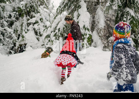 Vater, drei Kindern und einem Hund im Schnee spielen Stockfoto