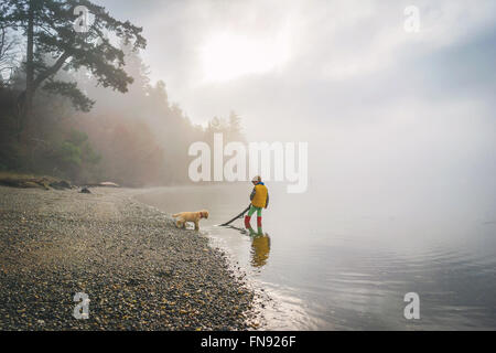 Junge und golden Retriever Welpen Hund spielen mit stick im Ozean Stockfoto