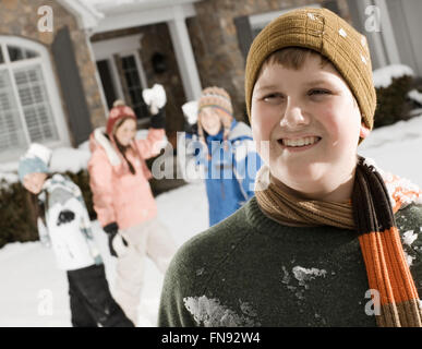 Winterschnee. Ein Junge in den Vordergrund und drei Kinder hinter ihm Vorbereitung Schneebälle zu werfen. Stockfoto