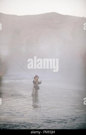 Frau Fischer Fliegen Fischen, stehend in Waders im tiefen Wasser Oberschenkel. Stockfoto