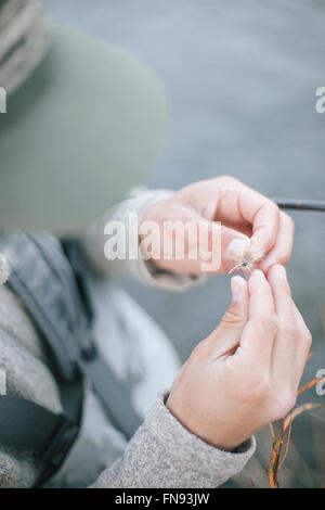 Eine Person, die Hände binden ein Fischen fliegen an einem Haken. Stockfoto