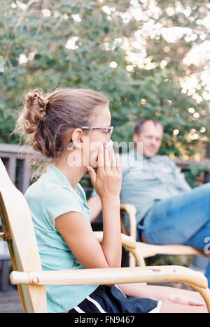 Ein reifer Mann und ein junges Mädchen in einem Garten sitzen. Stockfoto