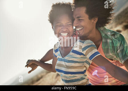 Ein paar mit ausgestreckten in einer Geste der Freiheit und der Aufregung, lehnt sich gegen den Wind. Stockfoto