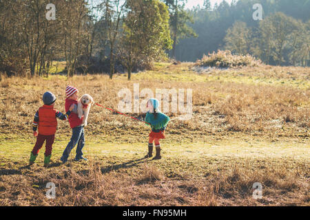 Drei Kinder spielen mit einem golden Retriever Welpe Hund Stockfoto