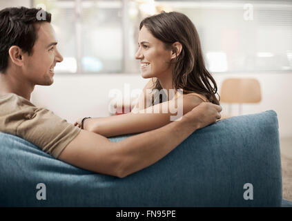 Ein junges Paar sitzt auf einem Sofa, Blick auf einander, ein Mann und Frau, Freund und Freundin. Stockfoto