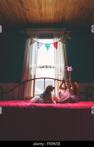 Mädchen sitzen auf Bett mit golden Retriever Welpe Hund spielen Stockfoto
