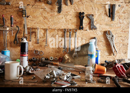 Eine Werkbank und Werkzeug Board in einem Zyklus-Werkstatt. Kaffee-Haferl, Handwerkzeuge, Schrauben und Muttern und Schraubenschlüssel. Stockfoto