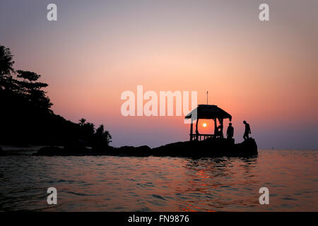 Silhouette von drei Personen am Strand bei Sonnenuntergang Stockfoto