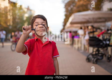 Kleiner Junge lächelnd durch Lupe, Sofia, Bulgarien Stockfoto