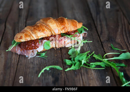 Croissant-Sandwich mit Parmaschinken, getrockneten Tomaten und Rucola Stockfoto