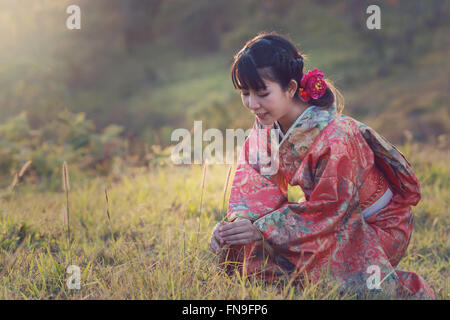 Frau im Kimono hocken im Feld Stockfoto