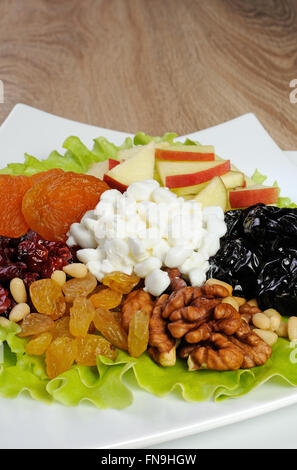 Salatblätter mit Nüssen, Äpfel, Trockenobst und Hüttenkäse in Kopfsalat Stockfoto