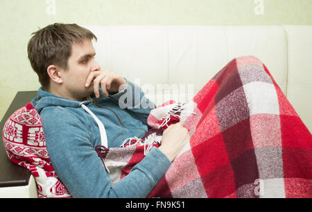 Kranker Mann auf Sofa zu Hause im Wohnzimmer Stockfoto