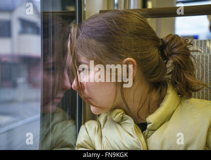 Teenager-Mädchen durch Zugfenster suchen und anhören von Musik auf Zug, Japan Stockfoto