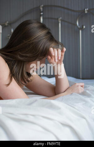 Depressive junge Frau Kopf in Händen im Bett Stockfoto