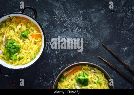 Asiatische Ei Nudelsuppe mit Gemüse und Schweinefleisch auf dunklem Schiefer. Ansicht von oben Stockfoto