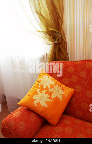 Orange Kissen mit Ornament auf einem roten sofa Stockfoto