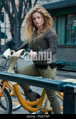 Blonde junge Frau in ihren Dreißigern zu fahren mit ihrem Fahrrad in Mailand, Italien, während der Winterzeit Stockfoto