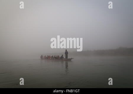 Chitwan Nationalpark, Nepal - 30. November 2014: Kanu mit Touristen auf einem Fluss im Morgennebel. Stockfoto