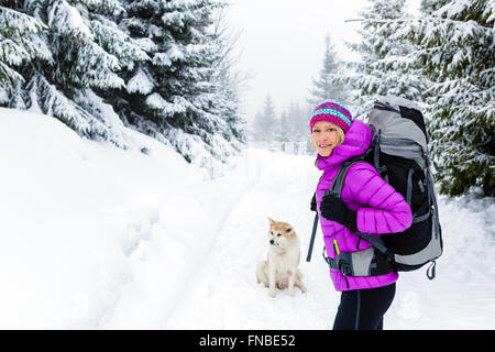 Wandern, trekking im Winterwald mit Akita Hund Frau. Erholung, Fitness und einen gesunden Lebensstil im Freien in der schönen Schnee Natur Stockfoto