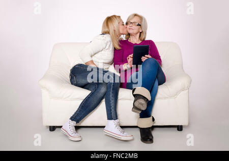 Junge Frau und ihre Mutter sitzt auf einer weißen Couch. Stockfoto
