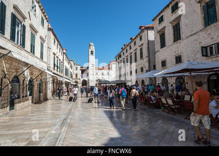 Touristen am Stradun (oder Placa) - Kalkstein-gepflasterte Fußgängerzone in der Altstadt von Dubrovnik, Kroatien. Ansicht mit Glockenturm Stockfoto
