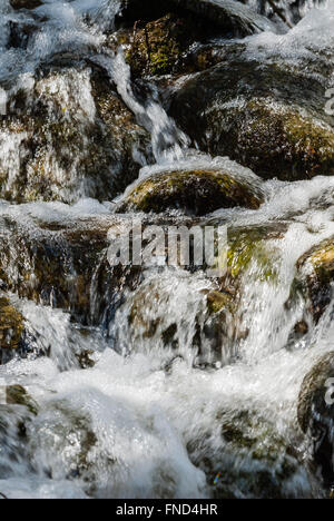 Motion Blur von Wasser über bemoosten Felsen. Stockfoto