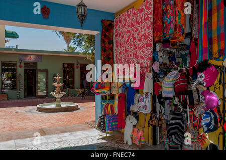 Farbenfrohe mexikanische Textilien + Wrestling Masken dekorieren eine Galerie von Geschäften mit Innenhof im alten Stadt San Jose del Cabo, Los Cabos. Stockfoto