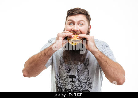 Hungrigen bärtiger junger Mann Essen Hamburger auf weißem Hintergrund Stockfoto