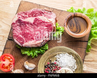 Ribeye Steak mit Gewürzen auf den alten Holztablett. Stockfoto