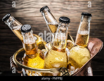 Kalte Flaschen Bier in den ehernen Eimer auf dem Holztisch. Stockfoto