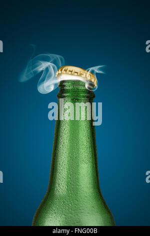 Grünen kalte Bierflasche mit Wassertropfen und goldene Kappe öffnen auf blauem Hintergrund Stockfoto
